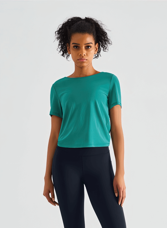 Woman wearing a stylish quick-drying open back sports T-shirt in solid green, short sleeves, made of breathable nylon.